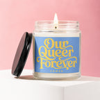 Glass candle with lit wick, blue label reads "Our Queer Forever Vowed".