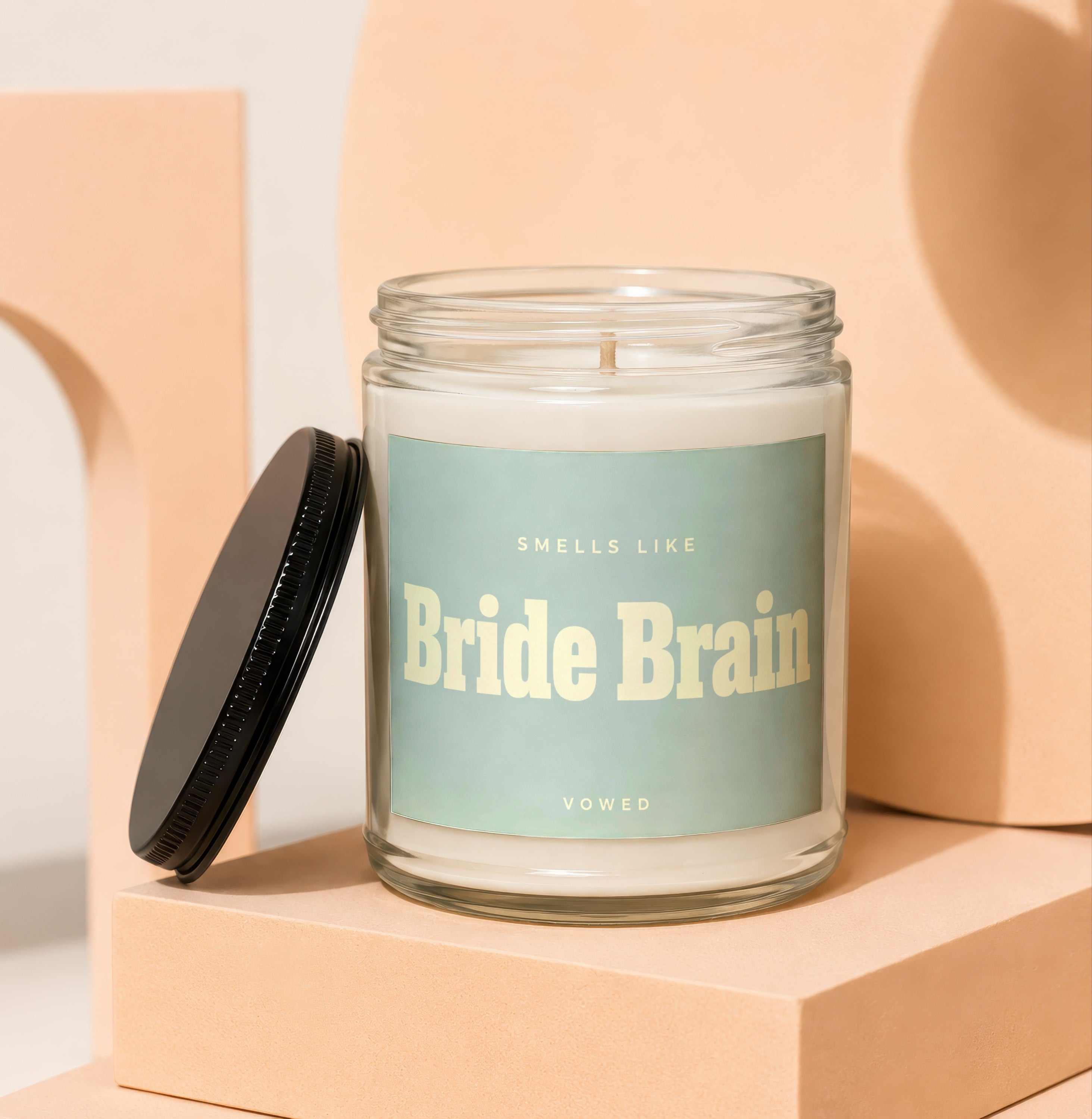 Glass candle with "Smells Like Bride Brain" text on a light blue label.