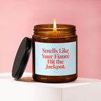 Amber jar candle with lit flame, "Smells Like Your Fiancé Hit the Jackpot" text.