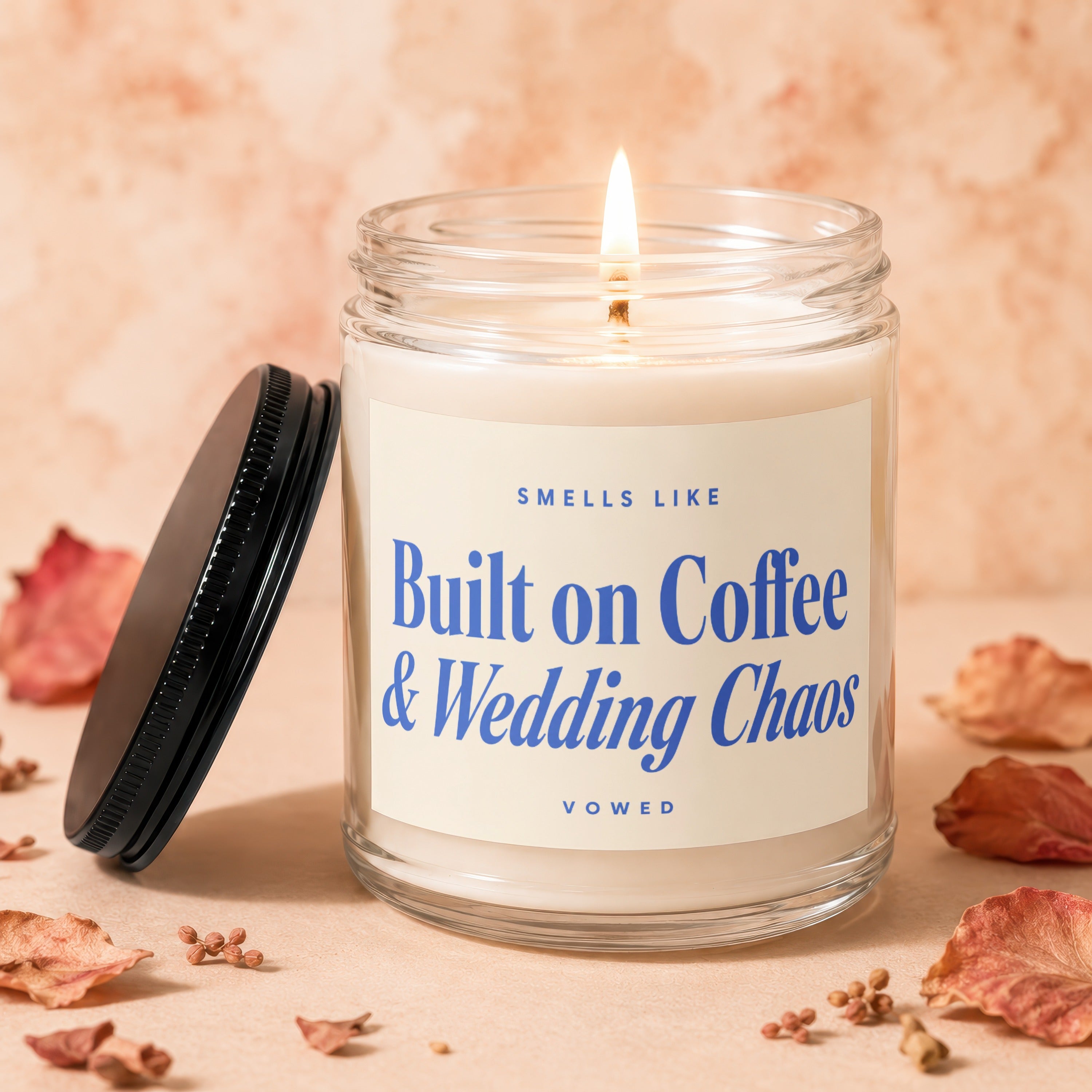 Lit candle with a label that reads "Sells Like Built on Coffee & Wedding Chaos Vowed."