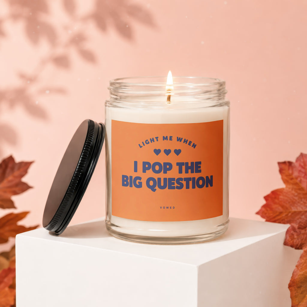 Glass candle with orange label reading "Light me when I pop the big question."