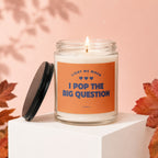 Glass candle with orange label reading "Light me when I pop the big question."