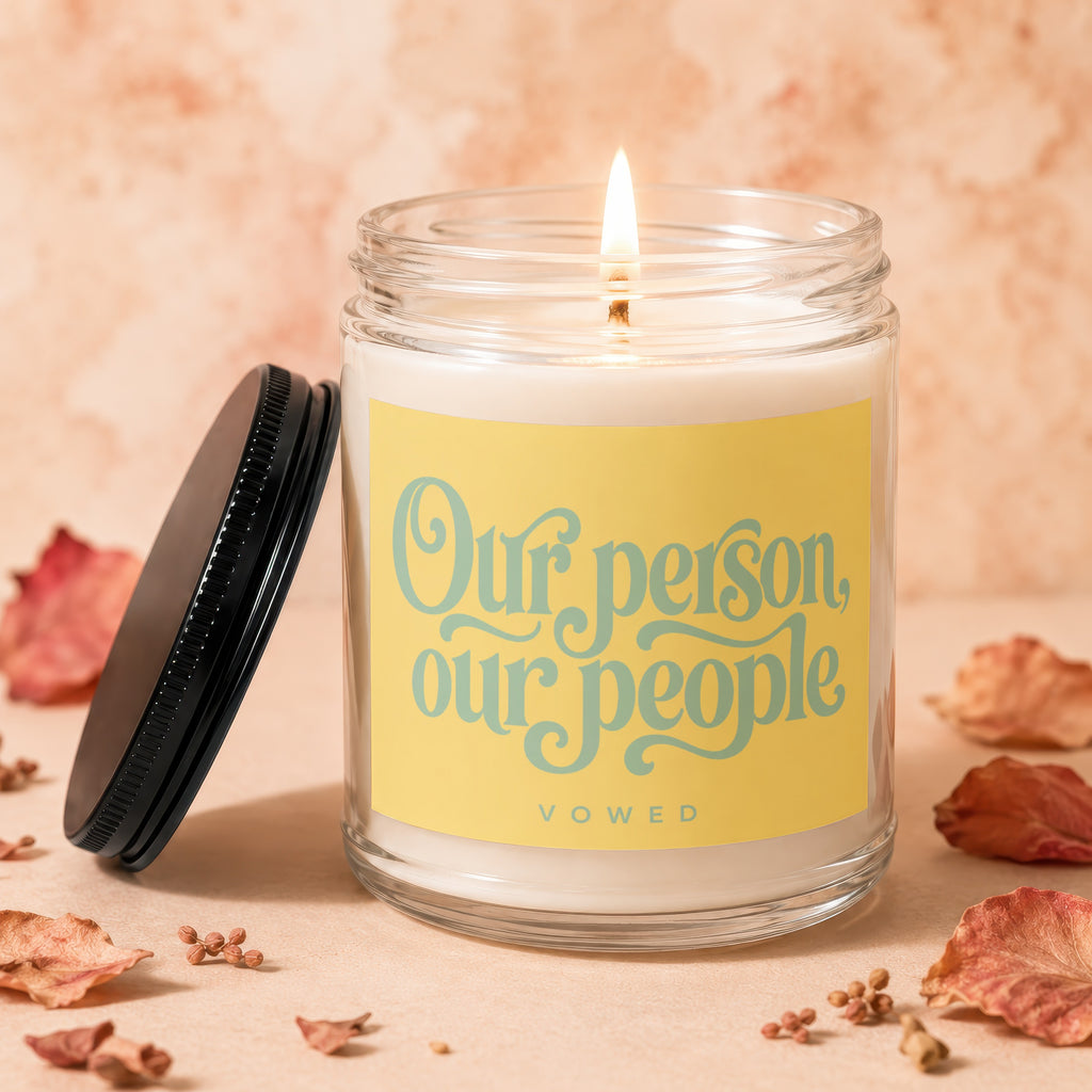 Lit candle in a jar with yellow label reading "Our person, our people VOWED".