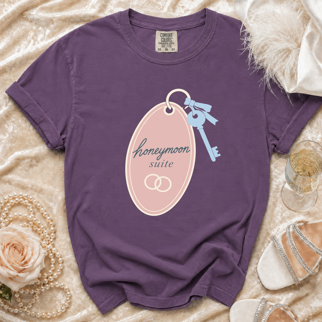 Purple t-shirt with "honeymoon suite" graphic, keys, and wedding rings.