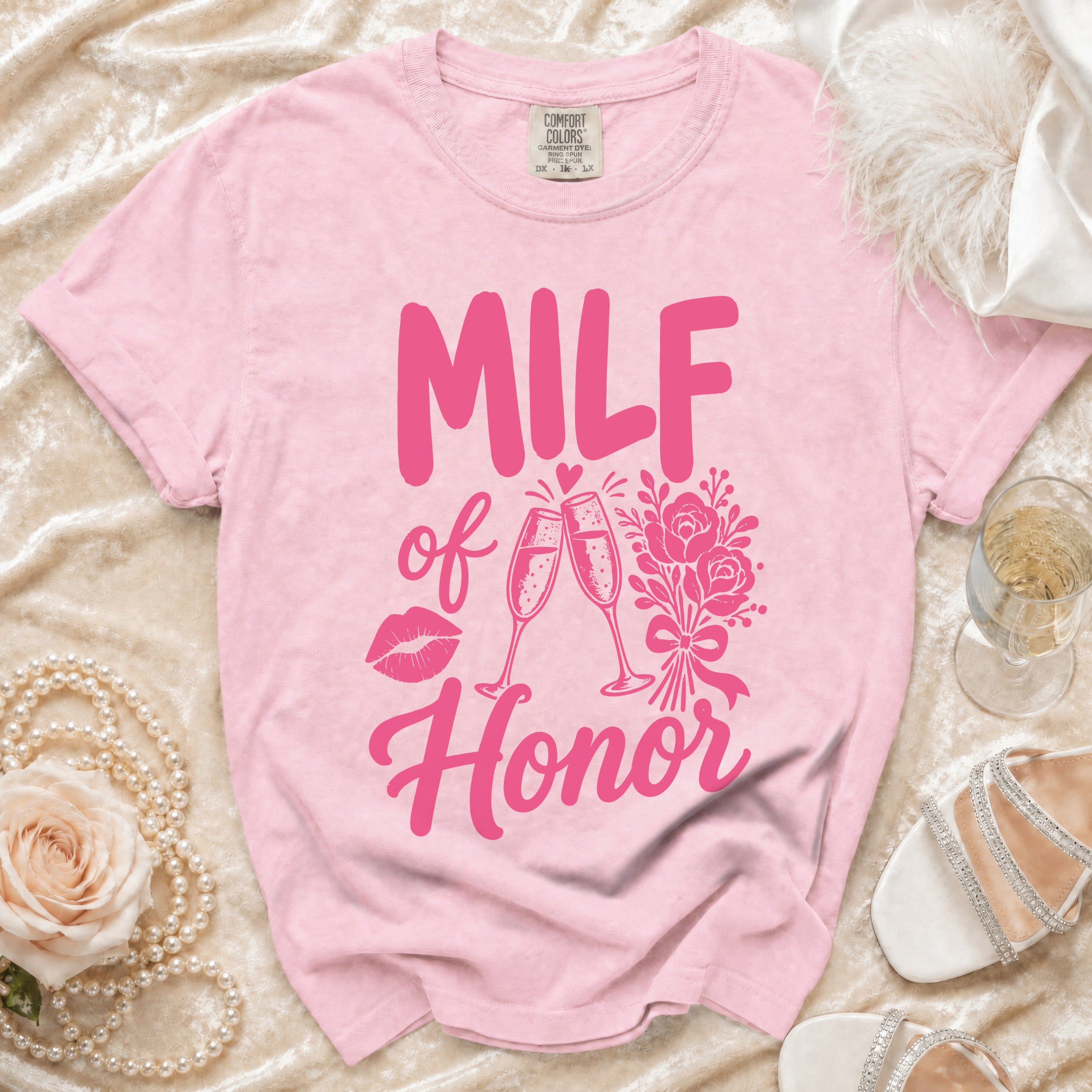 Pink t-shirt with pink "MILF of Honor" text, lips, champagne glasses, and flowers graphic.