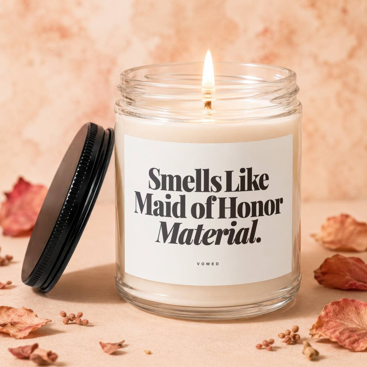 Candle with lid nearby, reading "Smells Like Maid of Honor Material. VOWED."