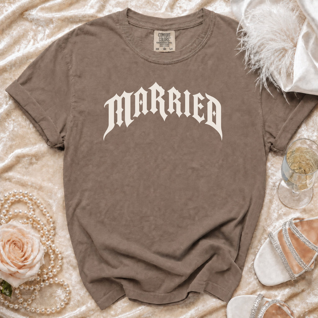 Brown t-shirt with "Married" in white gothic font, on a velvet surface with pearls and a rose.