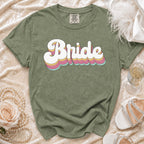 Sage green t-shirt with "Bride" in retro stacked lettering and wedding accessories.