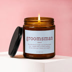 Amber jar candle with lit flame and lid off, reads "groomsman" definition.