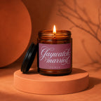 Lit amber glass jar candle with "Gaywatch: married vowed" text on pink label.