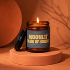 Amber jar candle with a lit wick and label reading "Moonlit Maid of Honor".