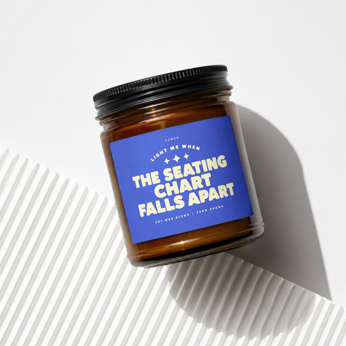 Amber candle with blue label: "Light me when the seating chart falls apart."