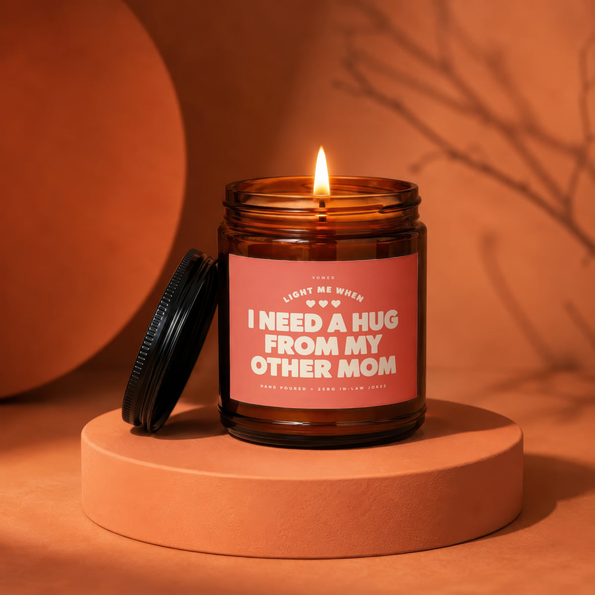 Amber jar candle with lid off, reads "I need a hug from my other mom".