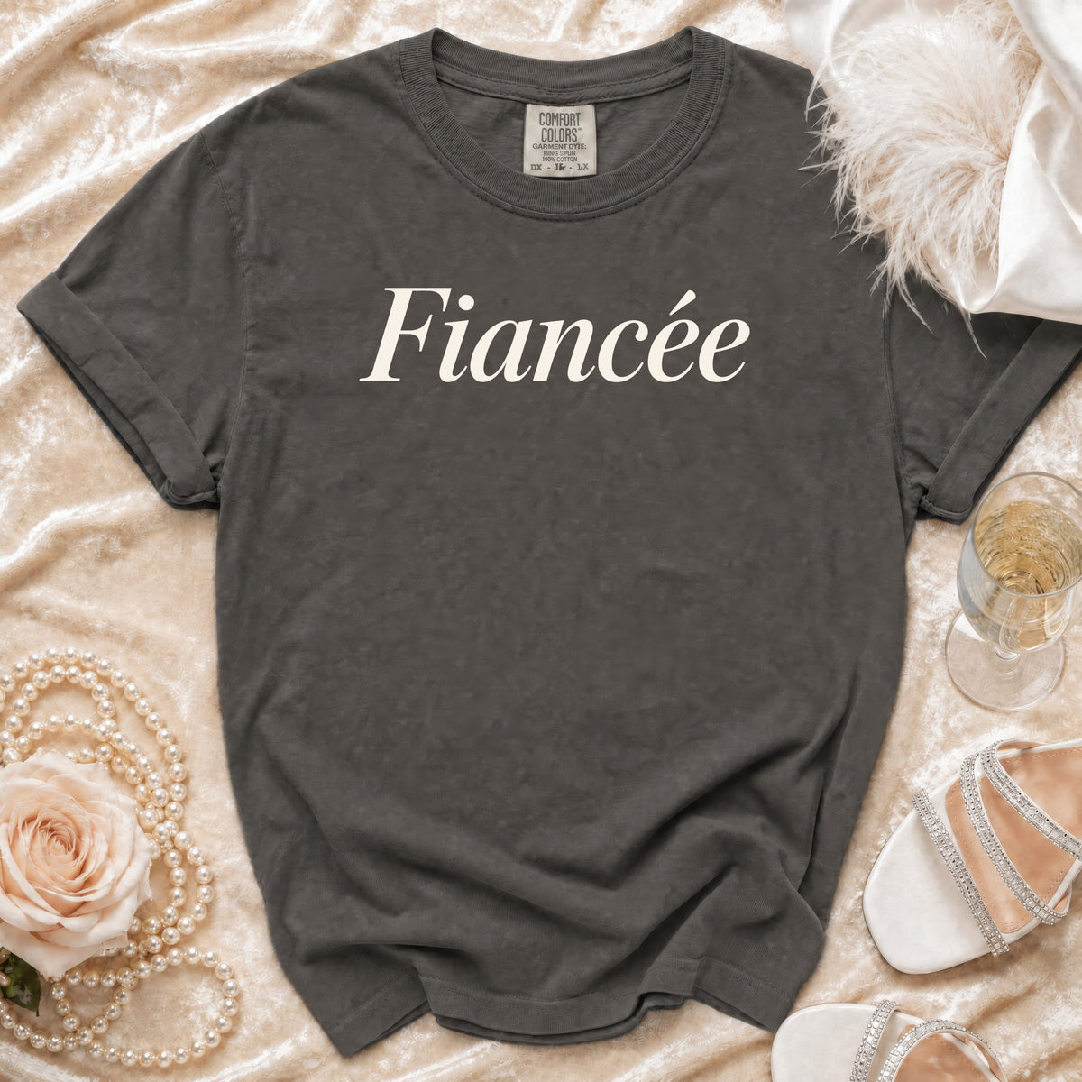 Dark grey t-shirt with "Fiancée" text, pearls, rose, champagne, and heels.
