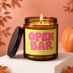 Amber jar candle with bright yellow label reading "OPEN BAR LOADING... VOWED".