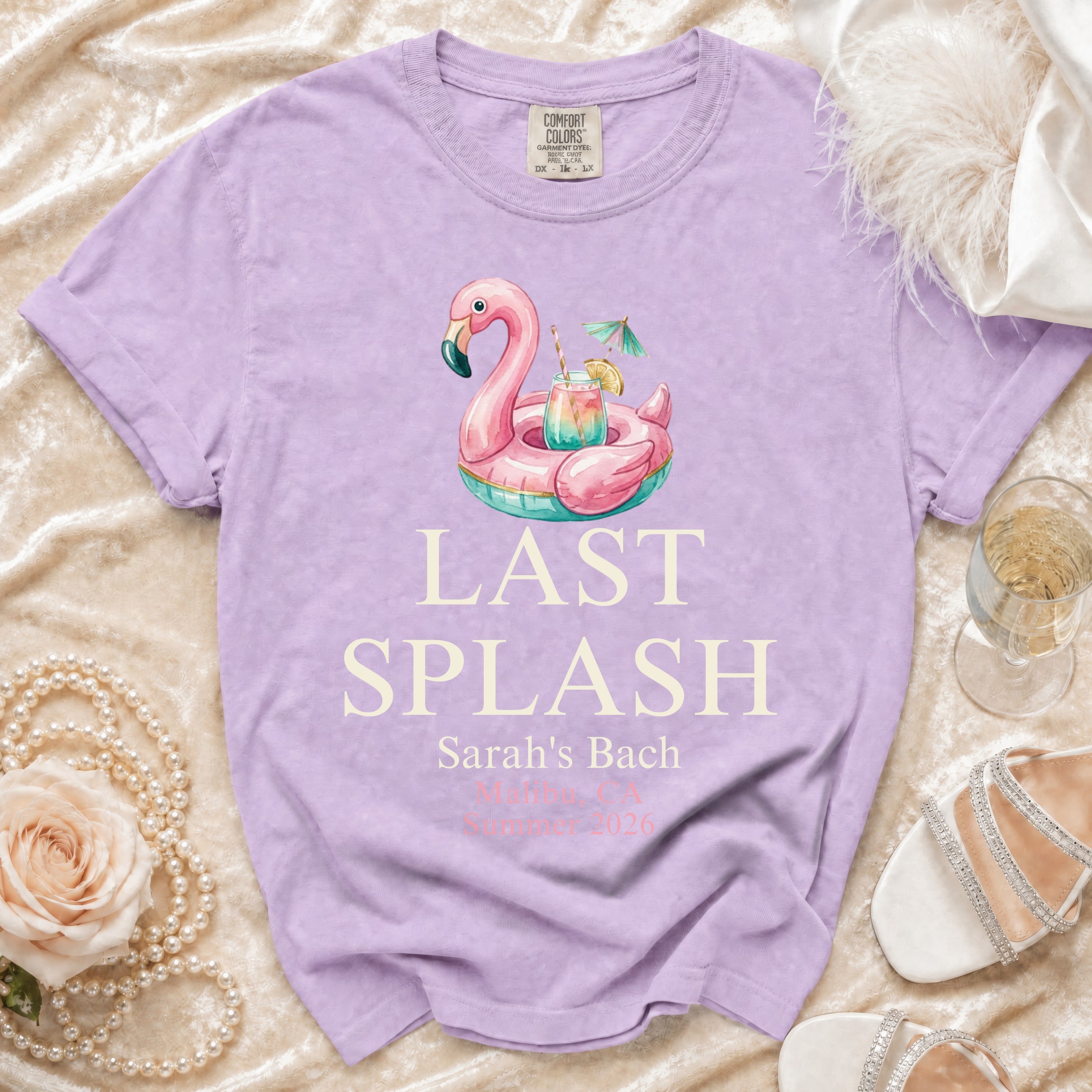Lavender t-shirt with pink flamingo float and "Last Splash Sarah's Bach 2026" text.