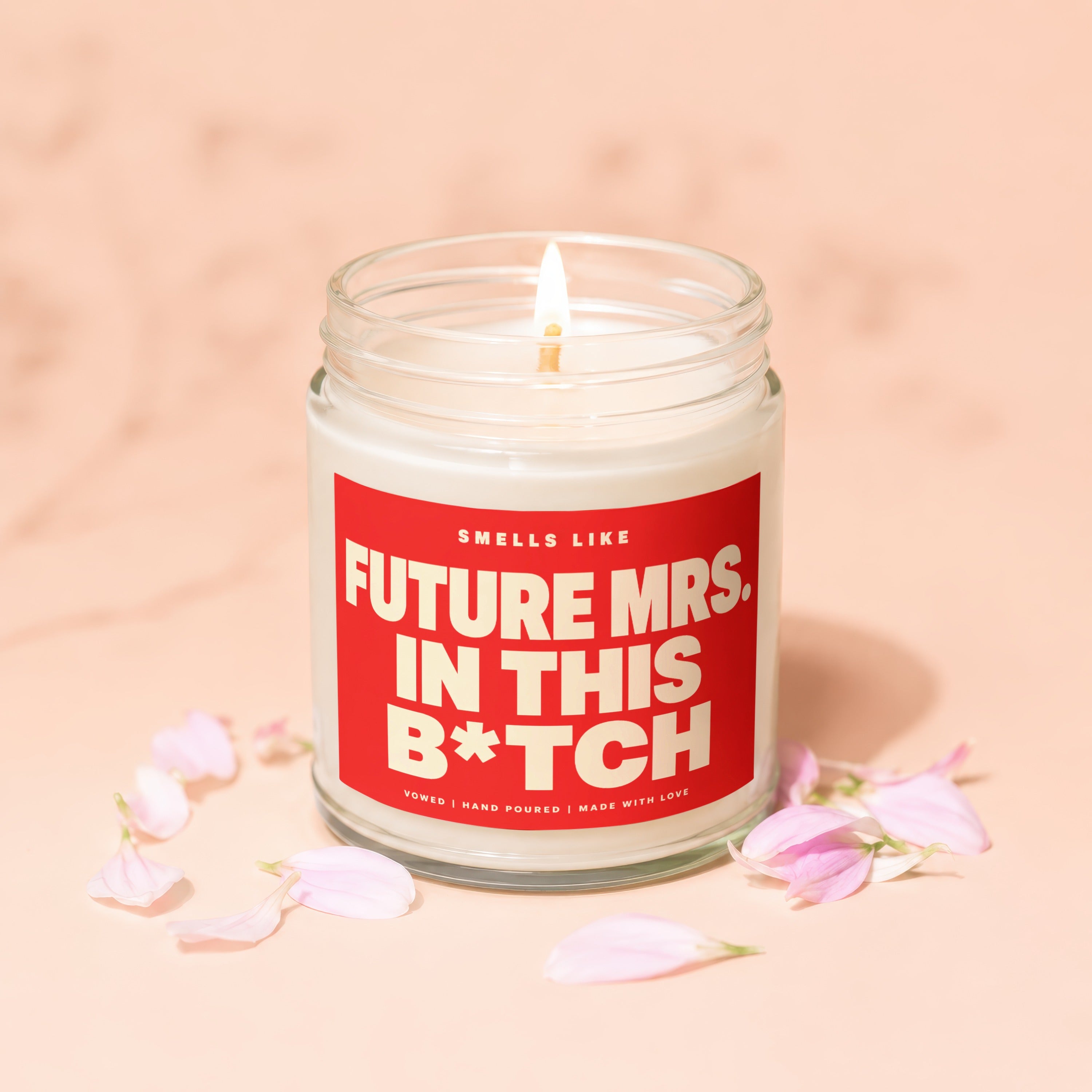Scented candle with red label, "Smells like Future Mrs. In This B*tch".