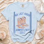 Light blue t-shirt with "Her Last Rodeo" and "Jennifer's Bach" text, cowboy boots graphic.