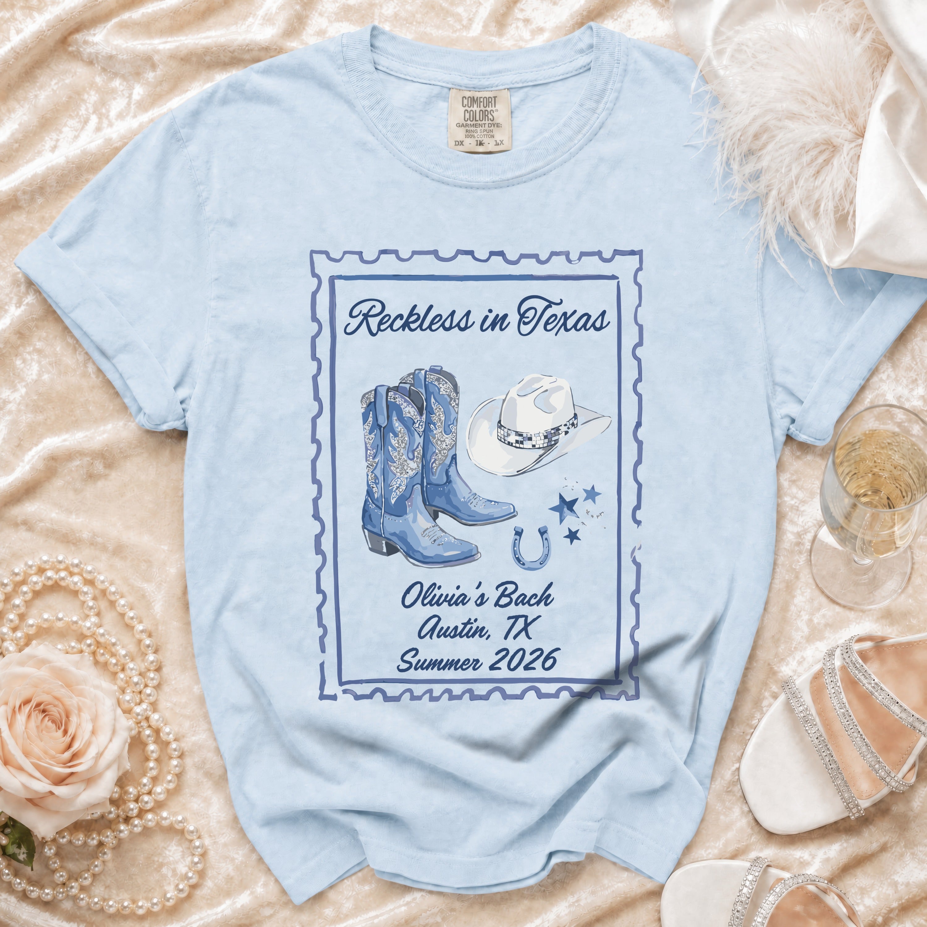 Light blue t-shirt with "Reckless in Texas" and "Olivia's Bach" graphics.