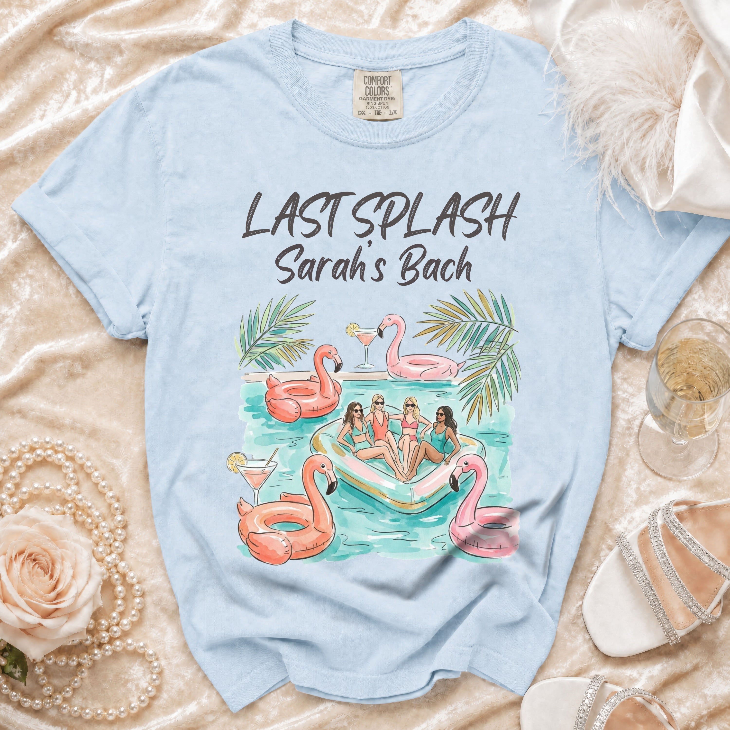 Light blue t-shirt with "Last Splash Sarah's Bach" and inflatable flamingos.