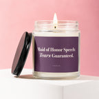 Glass candle with lit wick, black lid, and purple label reading "Maid of Honor Speech: Tears Guaranteed."