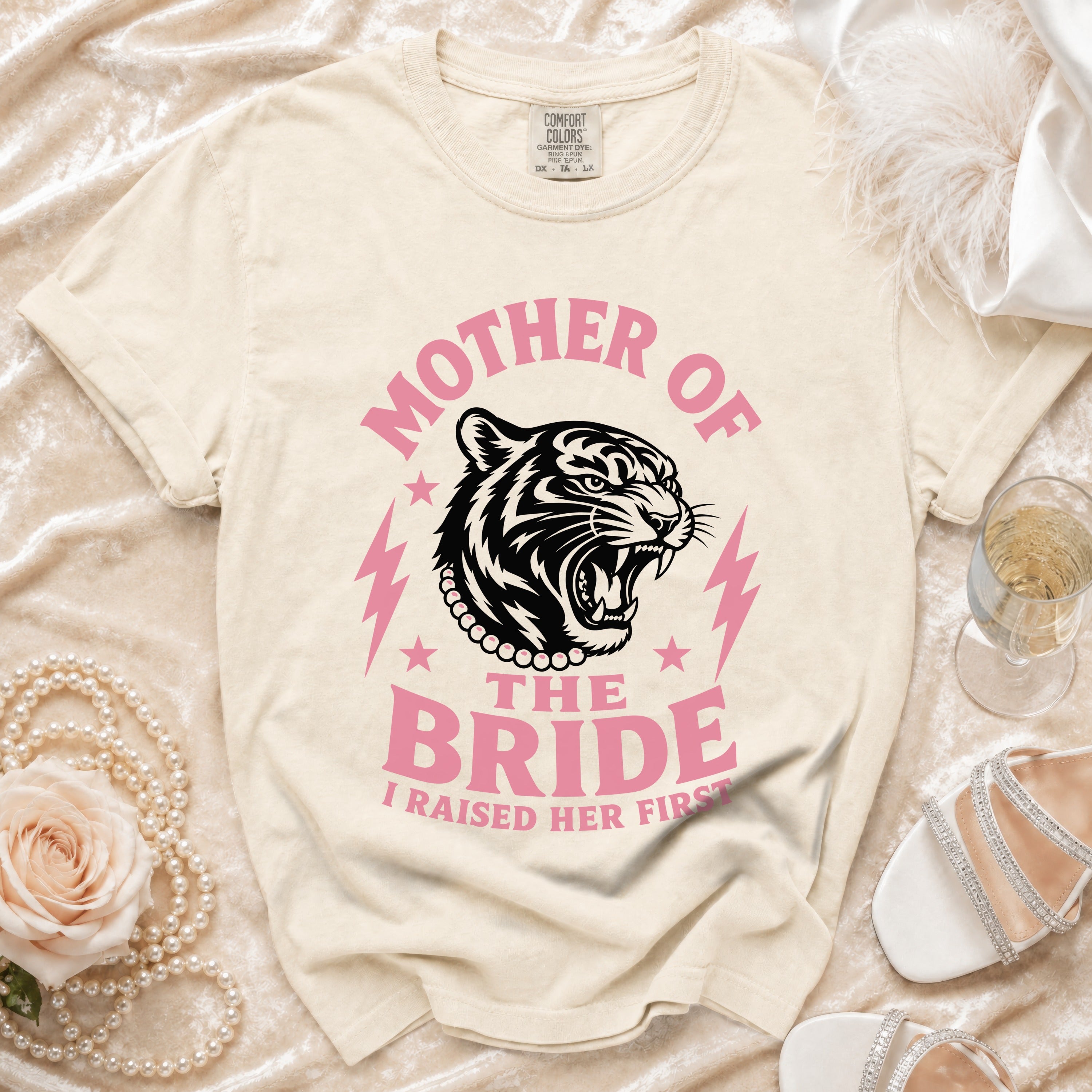 Cream t-shirt with pink text "MOTHER OF THE BRIDE I RAISED HER FIRST" and a tiger graphic.