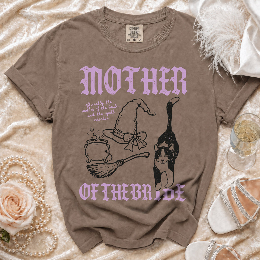 Brown crewneck t-shirt with purple and black graphics, witch-themed text, and accessories.