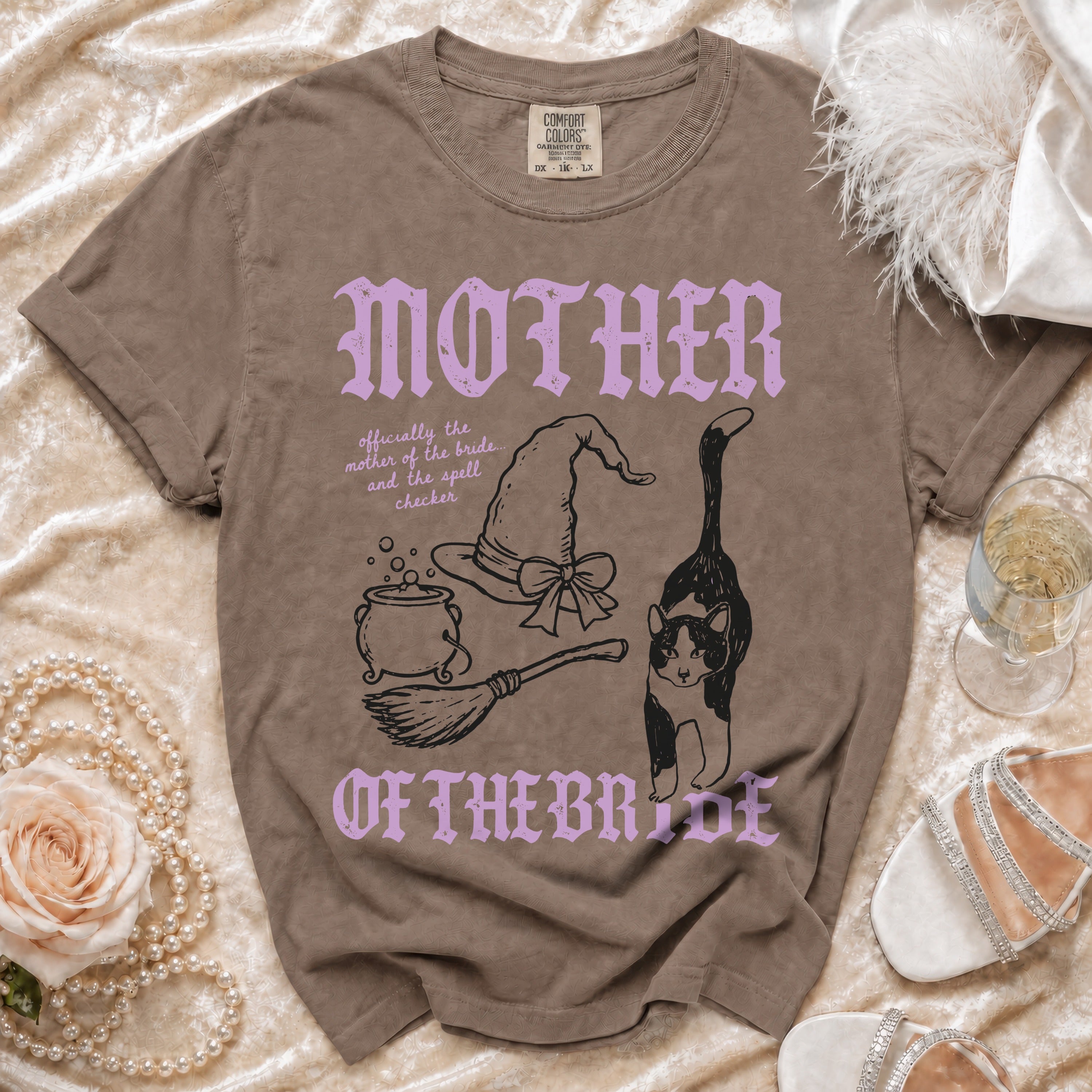 Brown crewneck t-shirt with purple and black graphics, witch-themed text, and accessories.