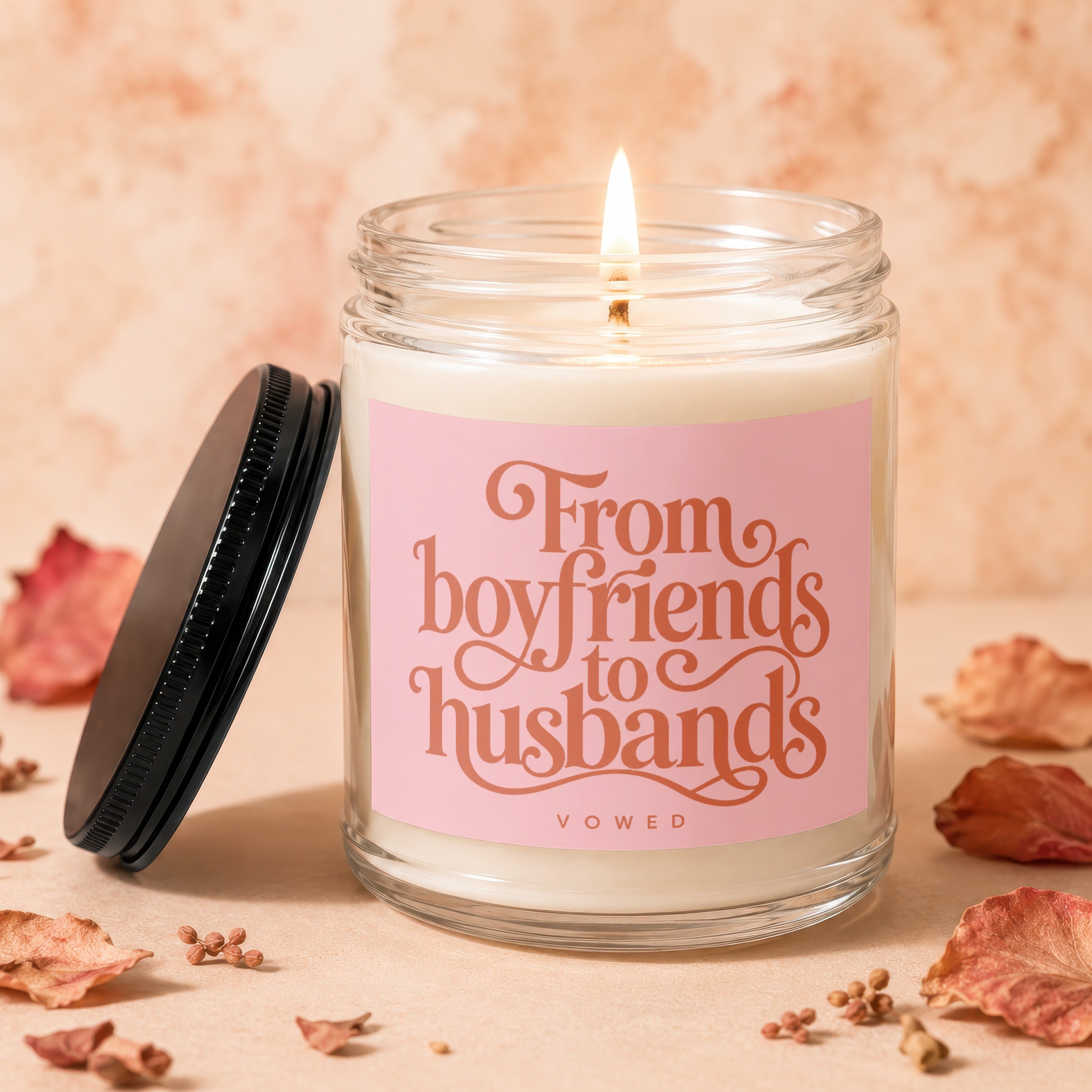 Candle with "From boyfriends to husbands" text on pink label, lid to the side.