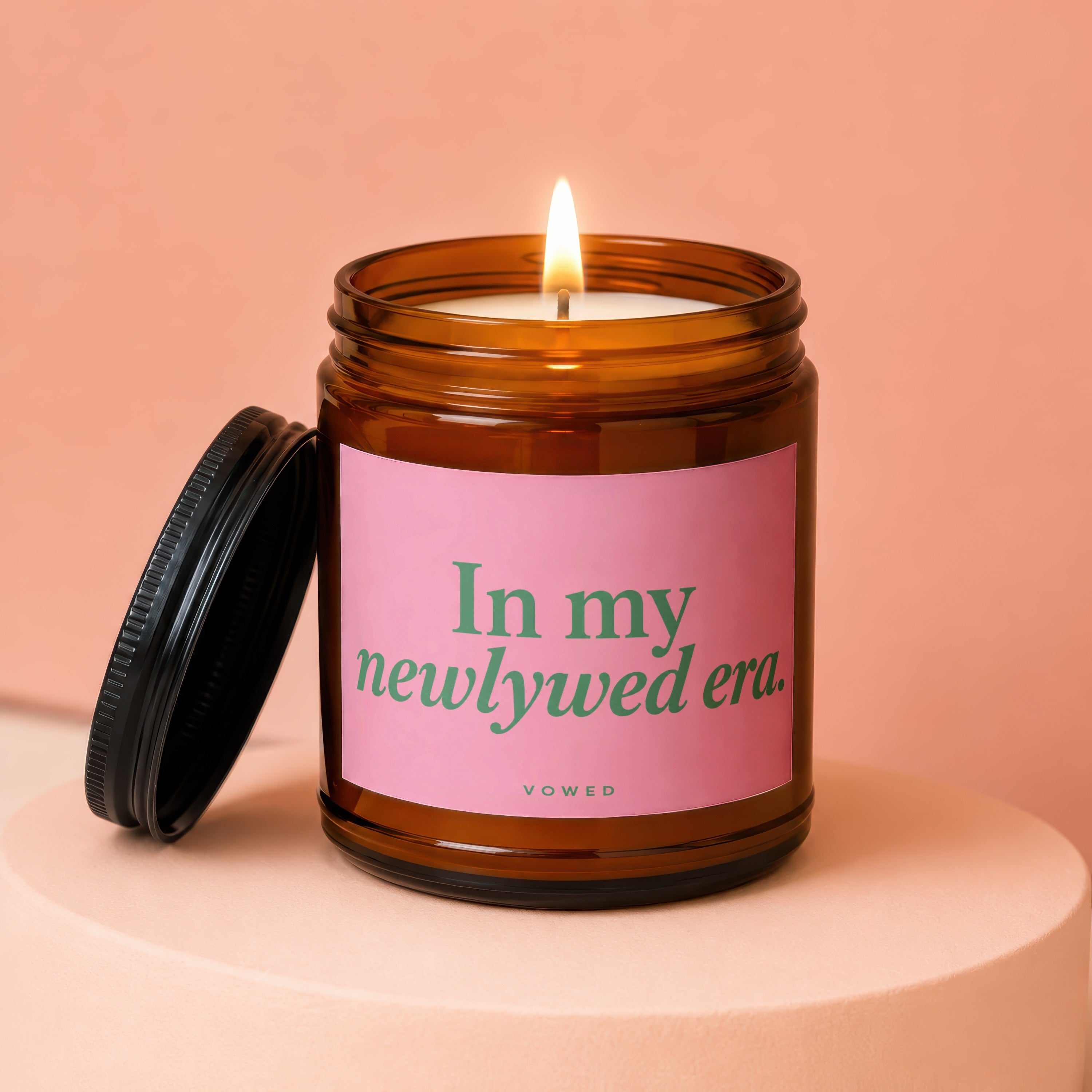 Amber jar candle with pink label reading "In my newlywed era."