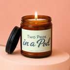 Amber glass candle with lit wick and "Two Peas in a Pod" label.
