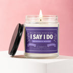 Candle with "I SAY I DO BRIDESMAID WANTED" label, lit wick, and black lid.
