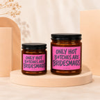 Two amber glass candles with pink labels reading "ONLY HOT B*TCHES ARE BRIDESMAIDS VOWED".