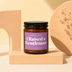 Brown glass candle, "I Raised a Gentleman" label, on display block.