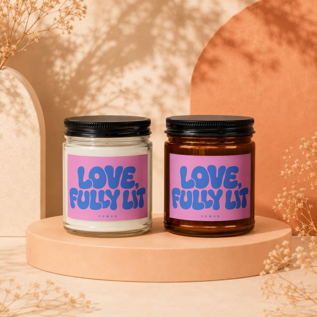 Two candles with purple labels that read "LOVE, FULLY LIT" display on pedestals.