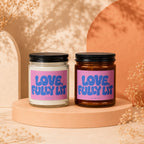 Two candles with purple labels that read "LOVE, FULLY LIT" display on pedestals.