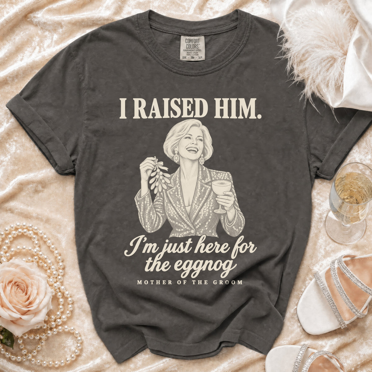 Charcoal gray t-shirt with an illustration of a woman holding mistletoe and eggnog, featuring text "I RAISED HIM. I'm just here for the eggnog, MOTHER OF THE GROOM".