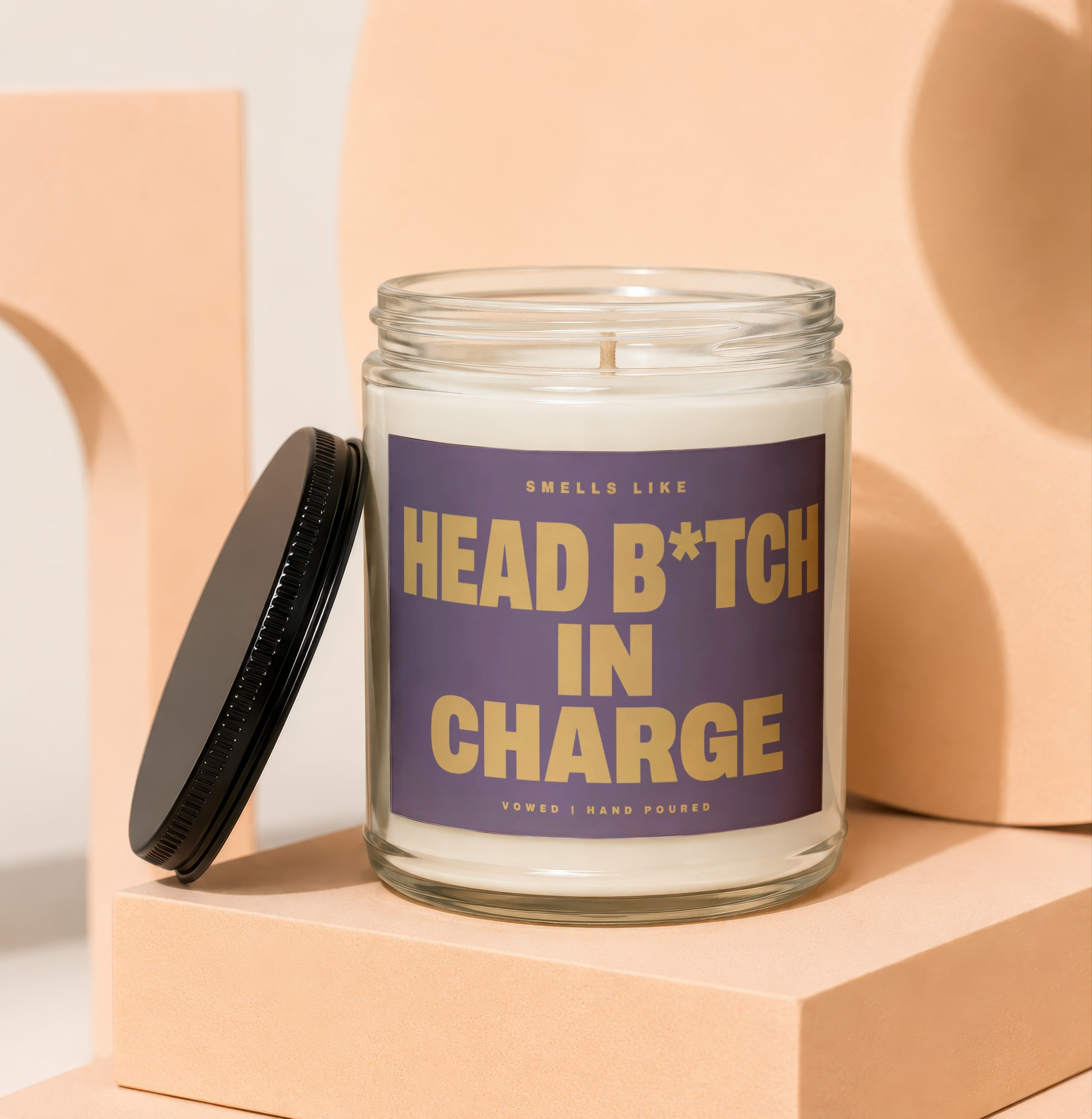 Glass candle with black lid, label reads "Smells like Head B*tch in Charge"