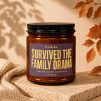 Amber jar candle with a label that reads "WARNING: SURVIVED THE FAMILY DRAMA SEATING CHART CLASSIFIED VOCWED".