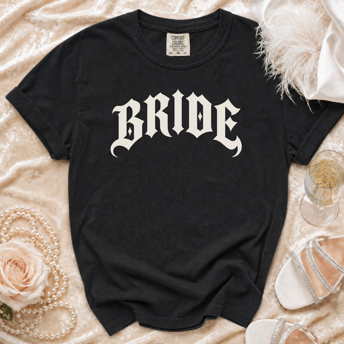 Black t-shirt with "BRIDE" in Gothic font, styled with pearls, rose, and heels.
