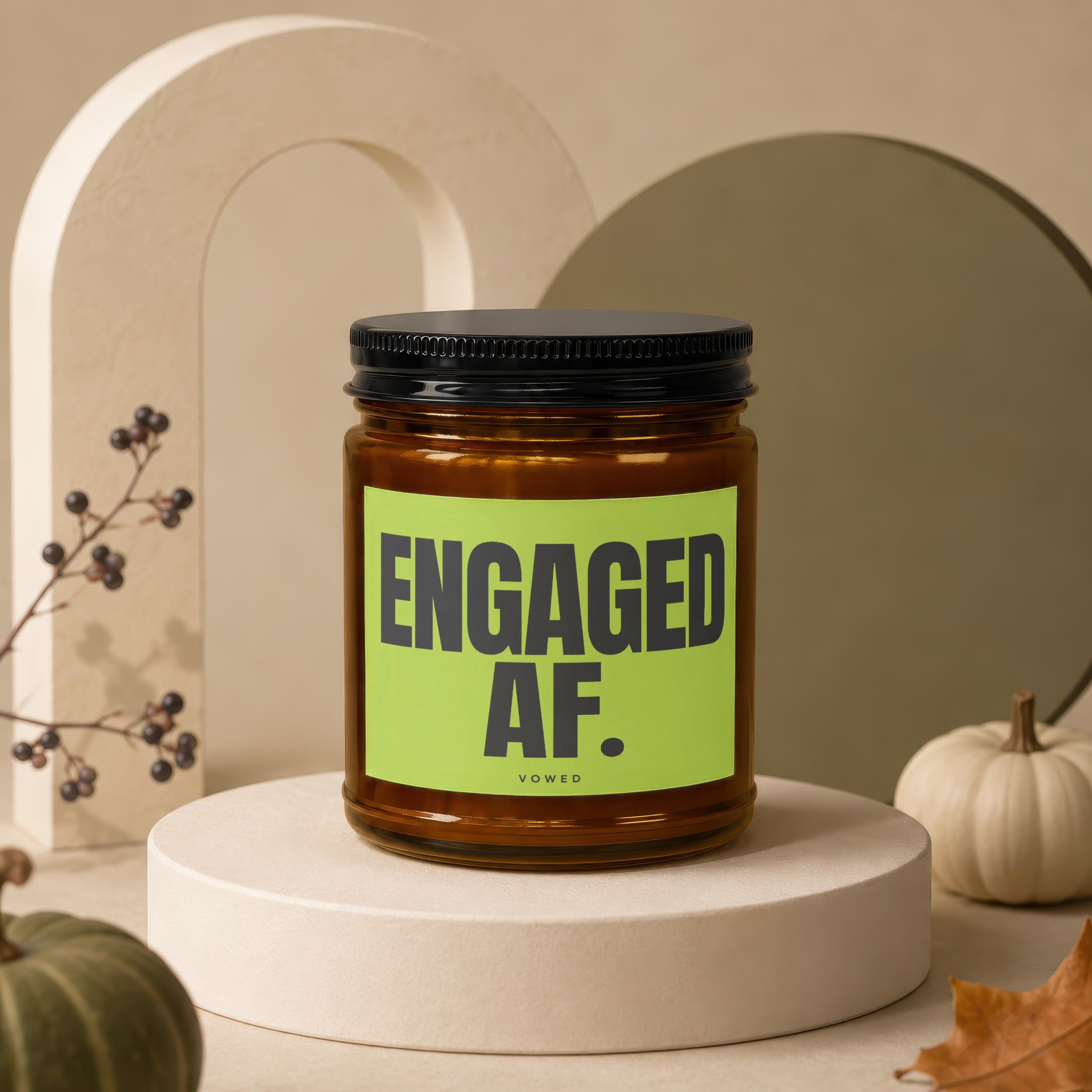 Candle with "ENGAGED AF." text on a green label, with decorative pumpkins and autumn leaves.