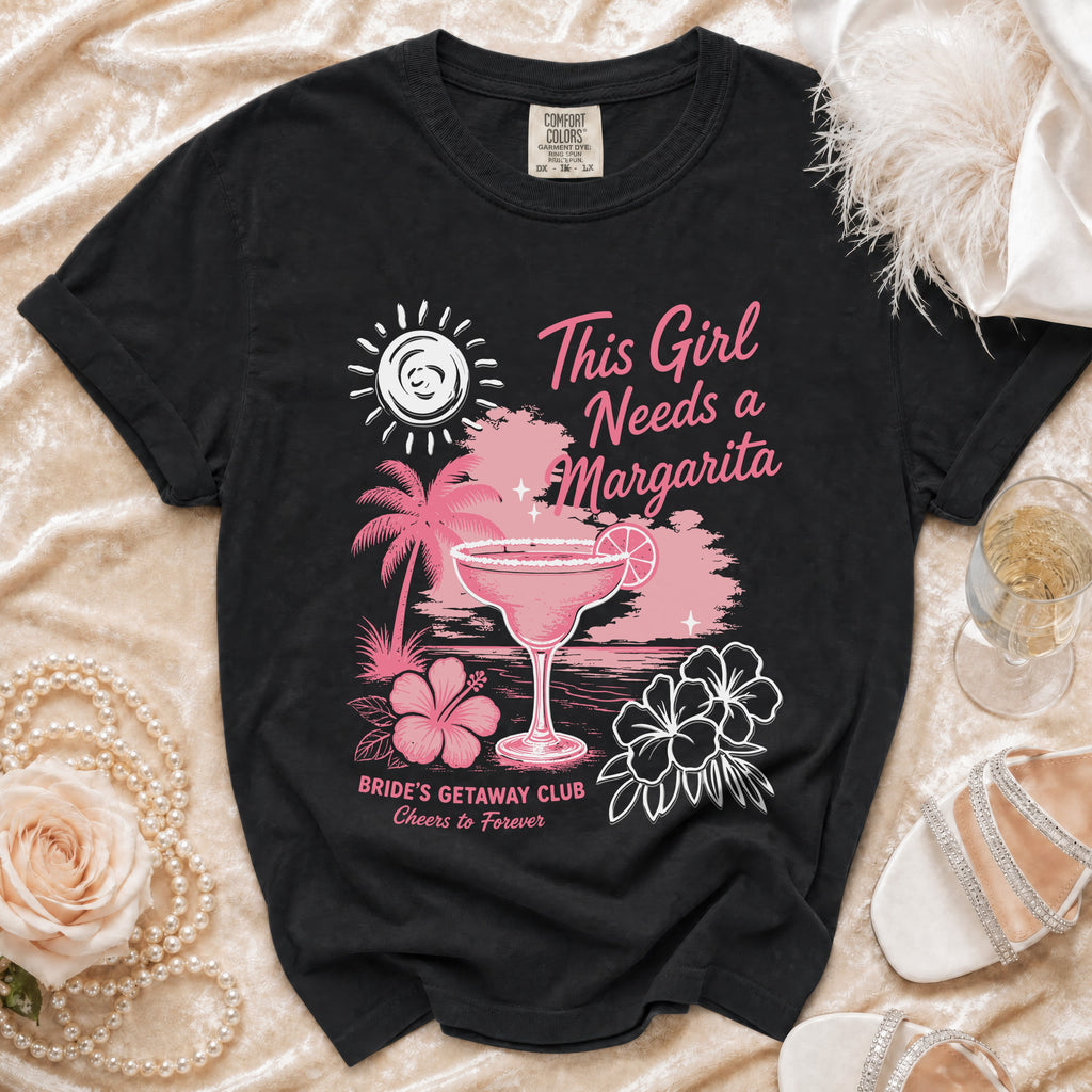 Black t-shirt with a tropical margarita, palm trees, and text: "This Girl Needs a Margarita Bride's Getaway Club Cheers to Forever".