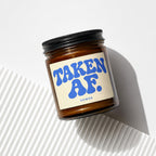 Amber jar candle with label reading "TAKEN AF. VOWED".
