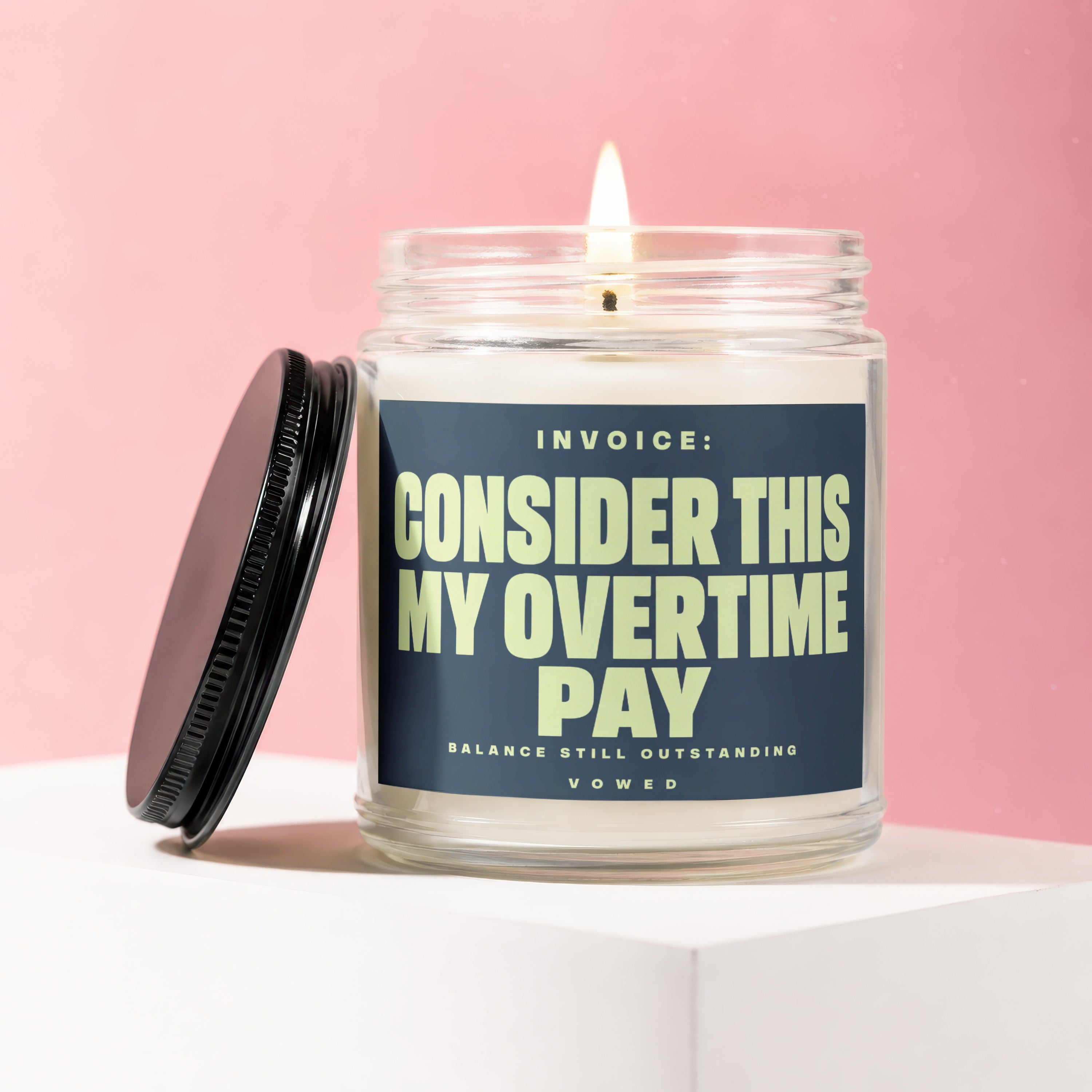 Glass jar candle with label reading "Invoice: Consider This My Overtime Pay."