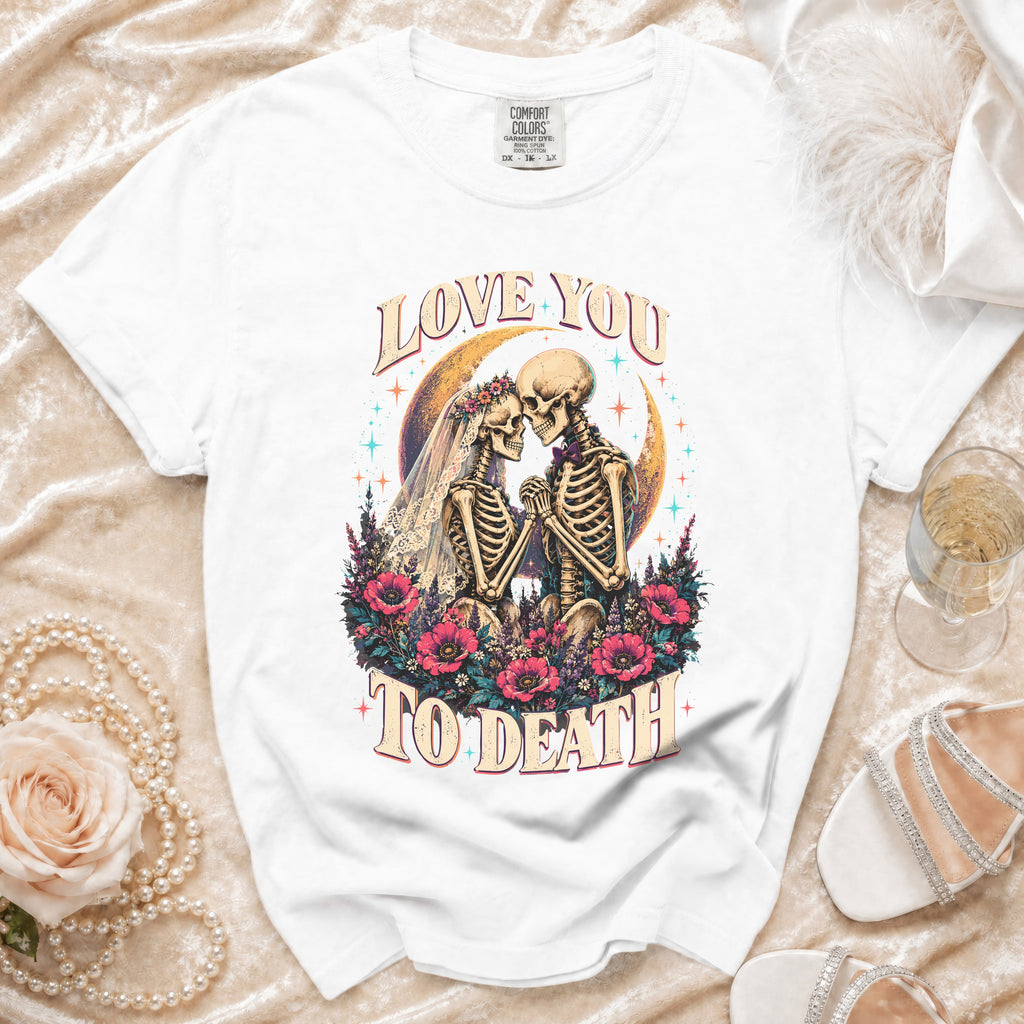 White t-shirt with skeletons in wedding attire, "Love You to Death" text, flowers, and moon graphic.
