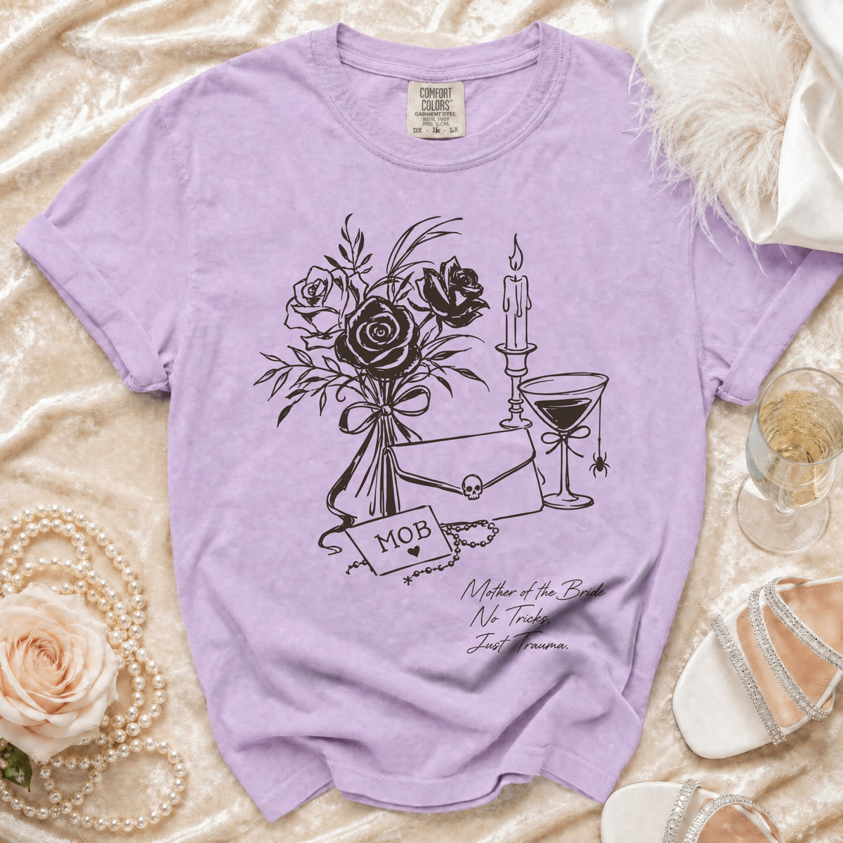 Lavender t-shirt with graphic of roses, clutch, skull, and text "MOB" and "Mother of the Bride No Tricks Just Trauma."