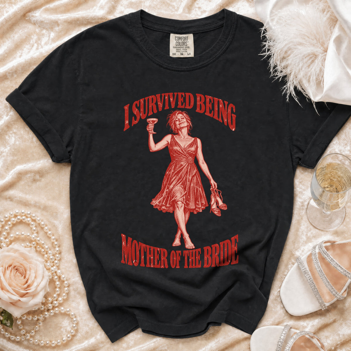 Black t-shirt with red graphic of a woman celebrating and text "I SURVIVED BEING MOTHER OF THE BRIDE".