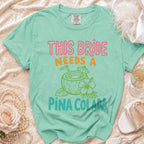 Comfort Colors t-shirt with "This Bride Needs A Pina Colada" text and coconut drink graphic.