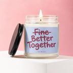 Glass candle with lid off, flame lit, and text "Fine Better Together"