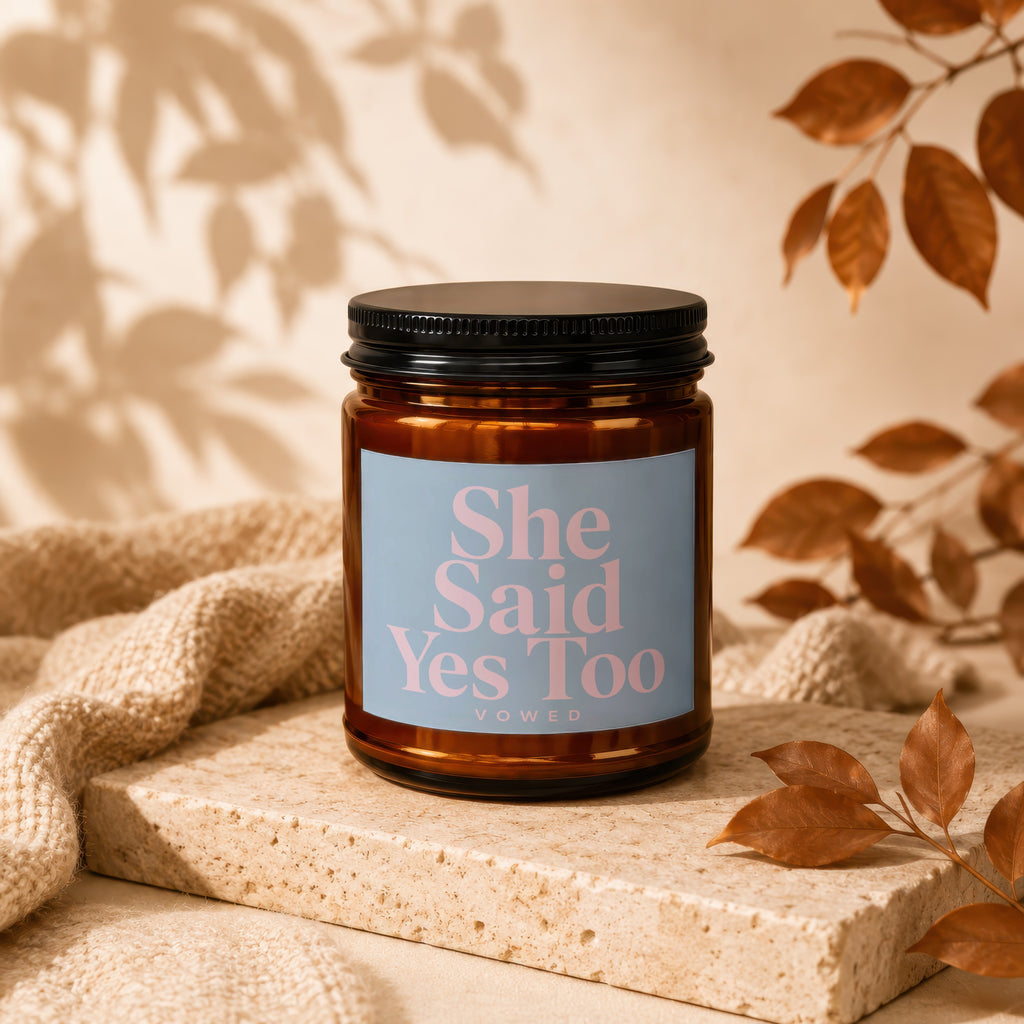 Brown glass candle with "She Said Yes Too VOWED" on a light blue label.